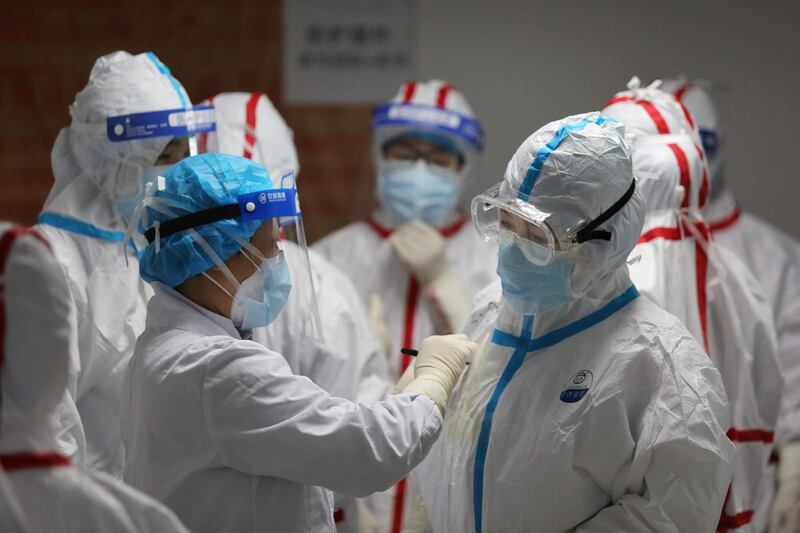Medical staff write messages on their protective suits before attending to COVID-19 coronavirus patients at the Red Cross Hospital in Wuhan in China's central Hubei province on March 16, 2020. China reported 12 more imported cases of the novel coronavirus on March 16 as the capital tightened quarantine measures for international arrivals to prevent a new wave of infections. - China OUT
 / AFP / STR

