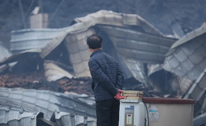 A resident looks at a gutted house after a massive fire engulfed the area in Sokcho, South Korea. EPA