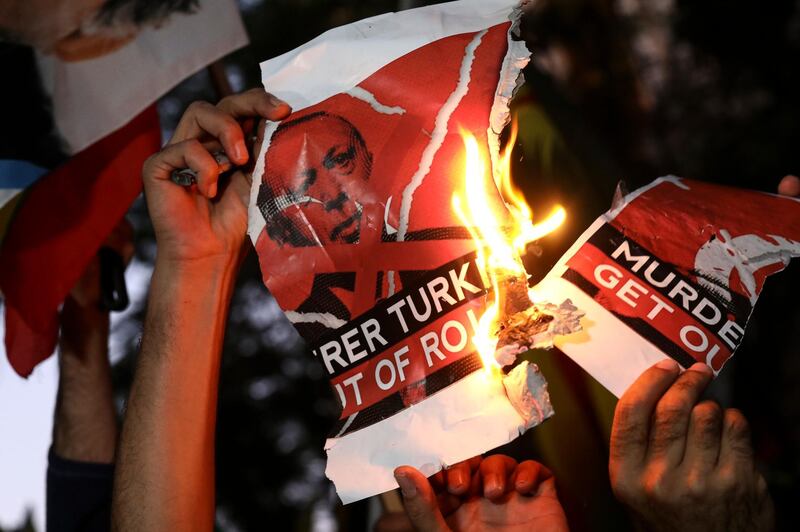Kurds living in Greece burn a banner depicting Turkish President Recep Tayyip Erdogan, during a rally against Turkey's military action in Syria, in Athens, Greece, Saturday, Oct. 12, 2019. The protesters, waving Kurdish flags as well as placards pledging support for Syria's Kurdish population, chanted slogans condemning Turkey's military action and urged for the withdrawal of Turkish forces. (AP Photo/Yorgos Karahalis)