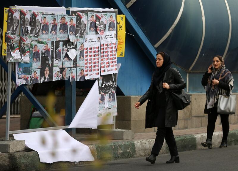 Iranian women walk past electoral posters. AFP