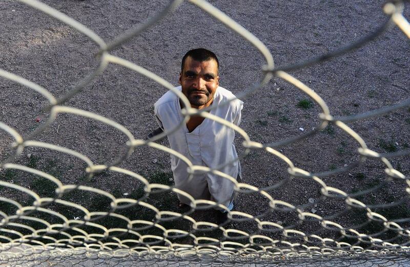 A male patient looks through a fence as he stands outside in the yard.