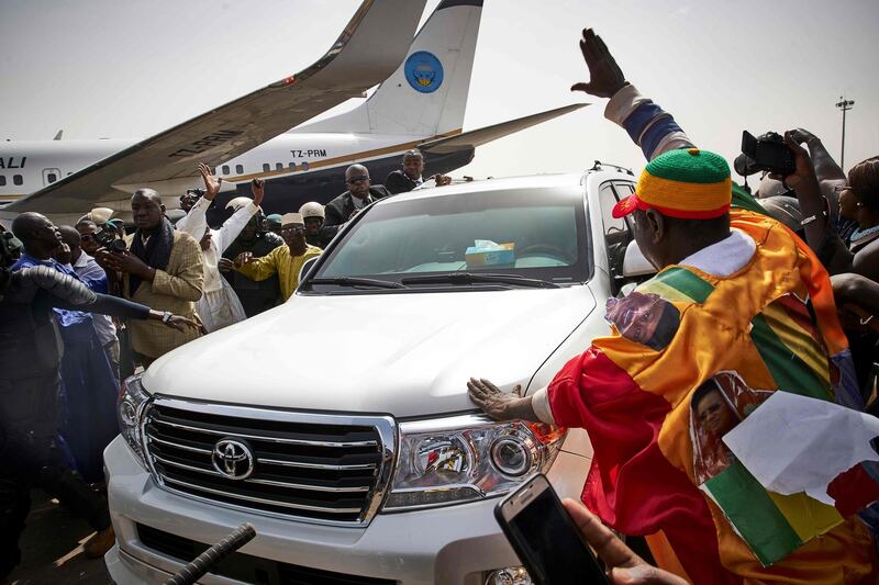 People greet former president Amadou Toumani Toure as he disembarks from a plane in Bamako, as he returns for the first time to Mali from living in exile in Senegal since a coup deposed him in 2012. Michele Cattani / AFP Photo.