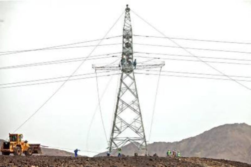 Workers adding an arm carrying electricity transmission lines on the transmission tower in Lahzoom, Ras al Khaimah. Jeff Topping/The National