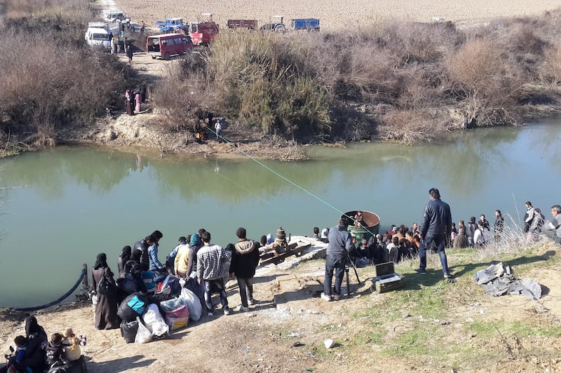 Displaced Syrians wait to cross the Orontes river into Turkey on February 5, 2014 at the Syrian-Turkish border in the Idlib province.  More than 130,000 people have been killed since the Syrian conflict began on March 2011, and more than 2.4 million Syrians have become refugees.  AFP PHOTO /SHAHBA PRESS/STR (Photo by STR / SHAHBA PRESS / AFP)