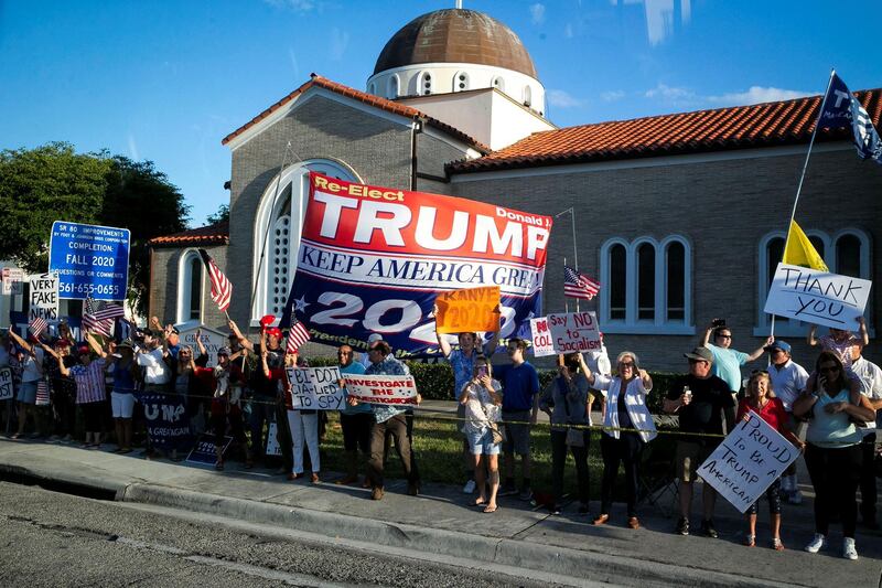 Supporters hold signs as Donald Trump's motorcade heads to his Mar-a-Lago club, in West Palm Beach, Florida, April 18, 2019. Reuters