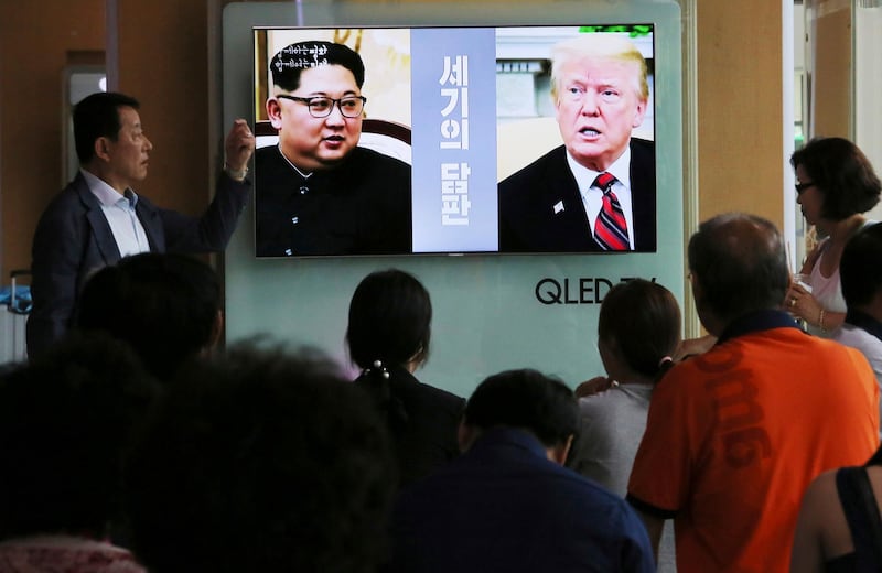 People watch a TV screen showing file footage of U.S. President Donald Trump, right, and North Korean leader Kim Jong Un during a news program at the Seoul Railway Station in Seoul, South Korea, Tuesday, June 5, 2018. The White House says Trump's meeting with Kim is set for 9 a.m. on June 12 in Singapore, which is 9 p.m. on June 11 on the U.S. East Coast. The signs read: " Negotiations of the century." (AP Photo/Ahn Young-joon)