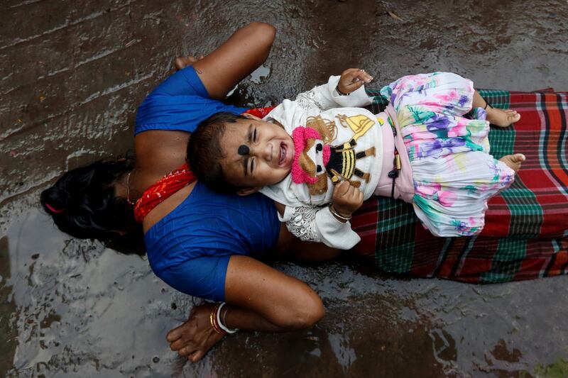 An infant lies on the back of a woman as she performs a ritual while worshipping Sheetala Mata, the Hindu goddess of smallpox, during Sheetala Puja in which devotees pray for the betterment of their family and society, in Kolkata, India. Reuters