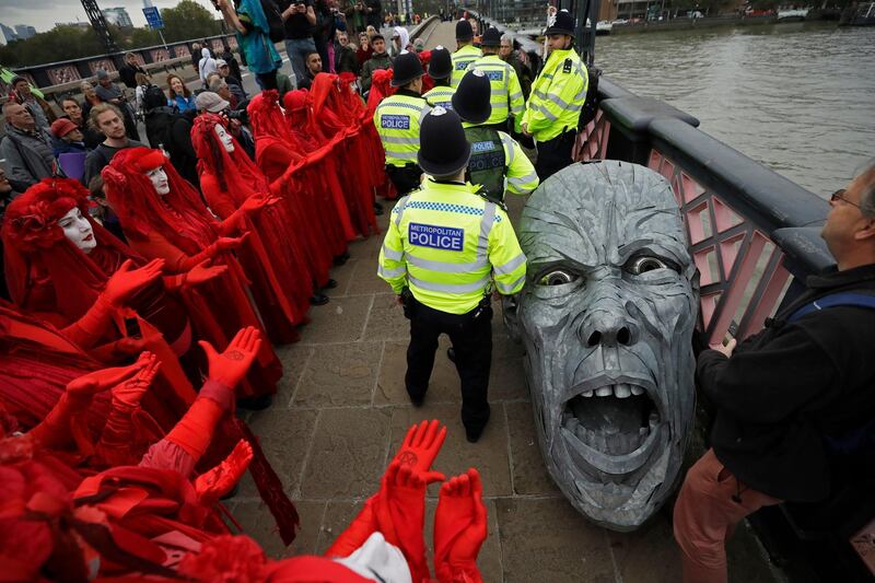 Environmental protesters gather around the head of a statue confiscated by police on Lambeth bridge in central London. Environmental activists were set to block roads leading to Britain's Parliament in an attempt to disrupt the heart of government. AP Photo