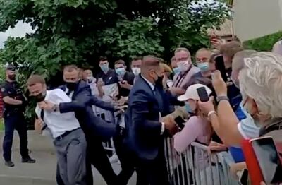 French President Emmanuel Macron is protected by a security member after getting slapped by a member of the public during a visit in Tain-L'Hermitage, France, in this still image taken from video on June 8, 2021. BFMTV/ReutersTV via REUTERS ATTENTION EDITORS - THIS VIDEO WAS PROVIDED BY A THIRD PARTY. THIS IMAGE WAS PROCESSED BY REUTERS TO ENHANCE QUALITY. UNPROCESSED VERSION OF THE VIDEO WAS PROVIDED SEPARATELY. NO RESALES. NO ARCHIVE. FRANCE OUT. NO COMMERCIAL OR EDITORIAL SALES IN FRANCE     TPX IMAGES OF THE DAY