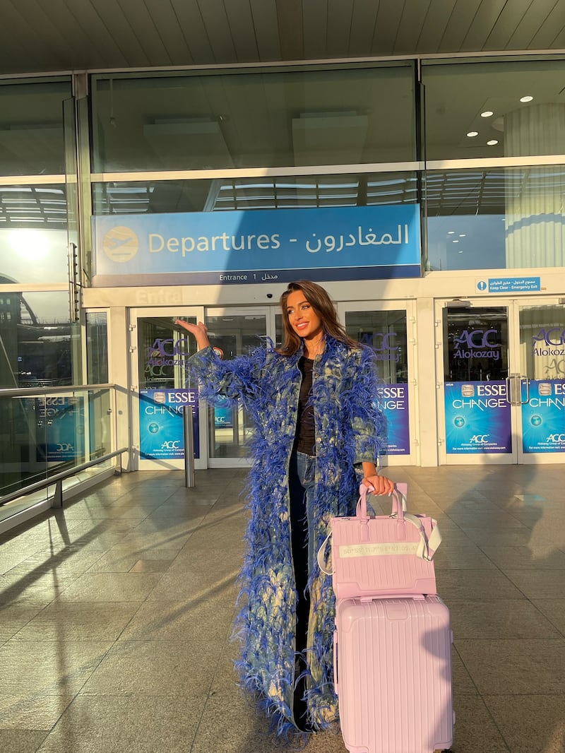 The Bahrain beauty queen departed from Dubai, wearing a long, blue-feathered couture jacket by Furne One over blue jeans. Photo: Miss Universe Bahrain
