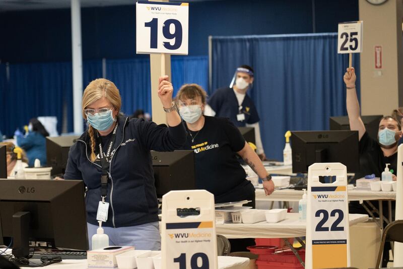 Healthcare workers hold up numbers showing they are ready administer more doses of the Covid-19 vaccine at a clinic outside of Morgantown, West Virginia. Willy Lowry / The National