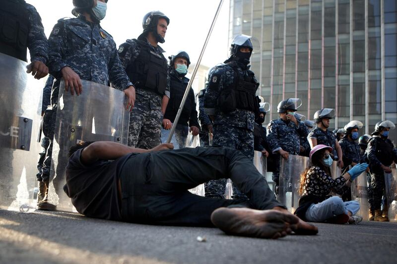 A barefoot Lebanese protester lies on the tarmac in front of riot police in the capital Beirut.  AFP
