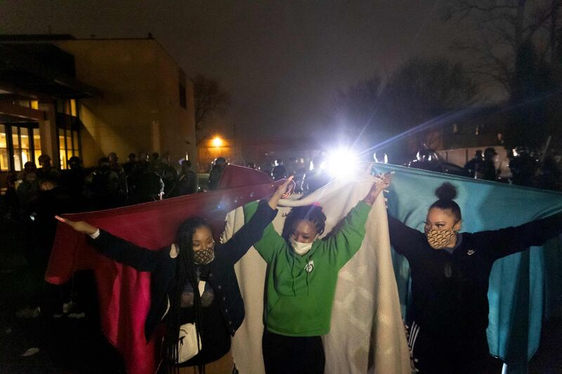 Protesters hold blankets to protect themselves from tear gas in front of the Brooklyn Centre Police Station as people gather to protest against the death of a man in police shooting in Minneapolis, Minnesota. AFP