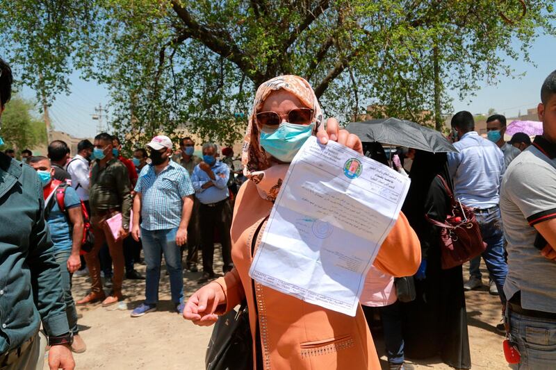 Rowaida Abdul Rahman shows her science master's degree certificate while jobless graduates gather in front of the Ministry of Oil to demand jobs in Baghdad, Iraq. AP
