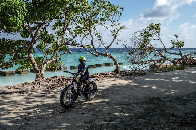 MAHIBADHOO, MALDIVES - DECEMBER 17: A boy rides his bike along an area of shoreline affected by coastal erosion, on December 17, 2019 in Mahibadhoo, Maldives. The Maldives is the worlds lowest lying country with a highest natural point of just 2.4 meters above sea level. As well as an increasing population, the nation faces a number of problems caused by climate change including rising sea levels, unpredictable weather, a shortage of drinking water, coastal erosion and declining fish stocks. With no rivers or streams on any of the islands, Maldivians have traditionally lived from fishing and except for Male and a handful of other islands, most islands rely on rain for drinking water and, increasingly, bottled water brought in from other islands. (Photo by Carl Court/Getty Images)