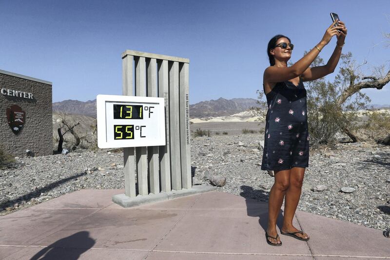 DEATH VALLEY NATIONAL PARK, CALIFORNIA - AUGUST 17: A visitor takes a photo in front of an unofficial thermometer at Furnace Creek Visitor Center on August 17, 2020 in Death Valley National Park, California. The temperature reached 130 degrees at Death Valley National Park on August 16, hitting what may be the hottest temperature recorded on Earth since at least 1913, according to the National Weather Service. Park visitors have been warned, ‚ÄòTravel prepared to survive.‚Äô (Photo by Mario Tama/Getty Images)