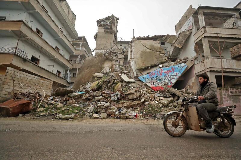 A Syrian man rides his motorcycle past a damaged building following an air strike by pro-regime forces on the rebel-held town of Ariha in the northern countryside of Syria's Idlib province.  AFP