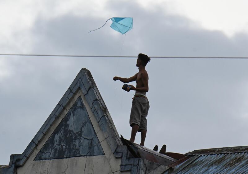 A resident flies his kite with rain clouds above atop his house inside a tenement building in Manila, as Typhoon Vongfong approaches.    AFP
