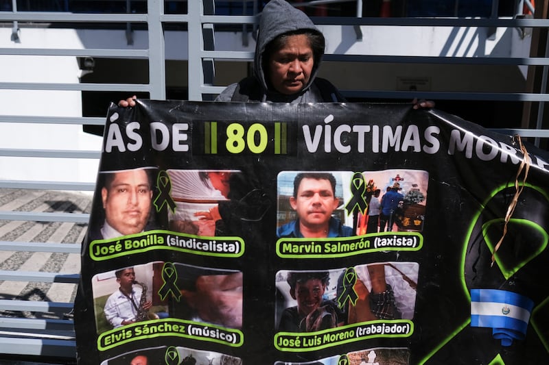 A woman holds a poster with pictures of people who died in detention during a protest outside the Attorney General's Office in Antiguo Cuscatlan. Reuters