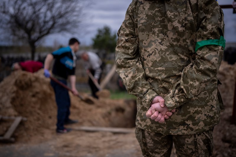 A Ukrainian soldier stands during the funeral of his father in Bucha, on the outskirts of Kyiv. AP