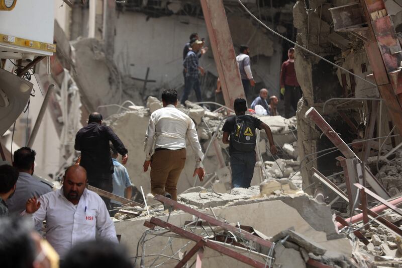 People gather at the site where the 10-storey building collapsed. Tasnim News  /  AFP