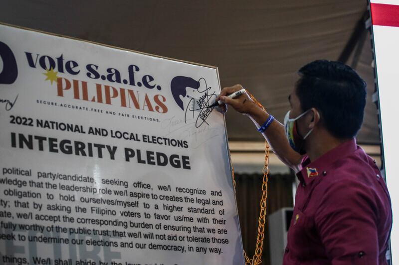 Manny Pacquiao signs a pledge as he files his certificate of candidacy to join the 2022 presidential race. Getty