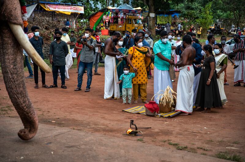 A child wearing a face mask as a precaution against the coronavirus looks at an elephant during Onam festival at the Vamana Hindu temple in Kochi, Kerala . AP