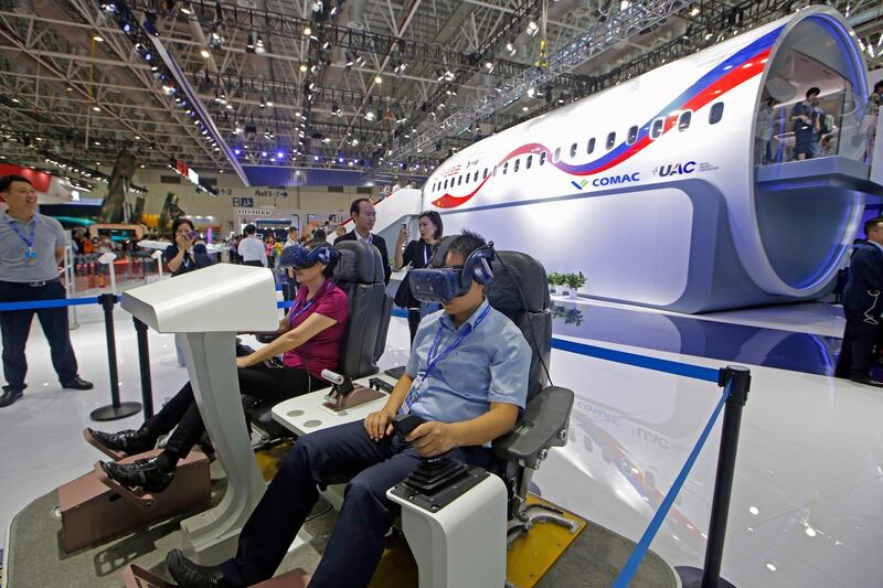 Visitors try out VR devices to drive a plane next to a full-size mock-up of the CR929 widebody jet during the 12th China International Aviation and Aerospace Exhibition. AP Photo