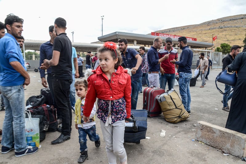 TOPSHOT - Syrian people carry their belongings as they cross the cilvegozu border gate to Turkish side on october 9, 2017 at Reyhanli district in Hatay.
The Turkish army has launched a reconnaissance mission in Syria's largely jihadist-controlled northwestern Idlib province in a bid to create a de-escalation zone, the military said on Monday. / AFP PHOTO / ILYAS AKENGIN