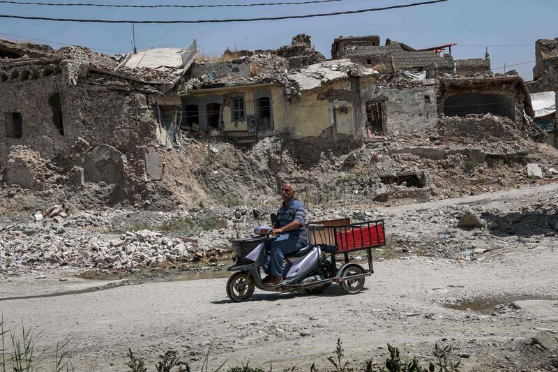 A man rides a scooter cart along a damaged street in the western part of Iraq's northern city of Mosul on August 10, 2019. Although Mosul was freed from the grip of Islamic State (IS) group jihadists in 2017, tens of thousands of displaced Iraqis native to the city remain dwelling in sprawling displacement camps instead of moving back home to its unlivable ruins. Many of them say they tried returning but were shocked by what they saw. Across Iraq, more than 1.6 million people remain displaced, among them nearly 300,000 from Mosul alone, according to the International Organization for Migration. / AFP / SAFIN HAMED
