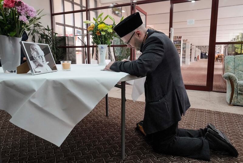 A man a writes a message of condolence in a book before the memorial. AP