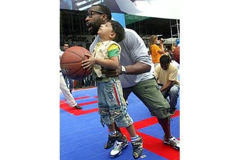 Baron Davis, of the Los Angeles Clippers, helps an Indian boy during a basketball awareness event in Mumbai in July 2009.