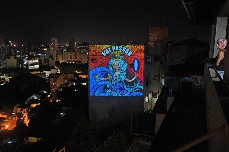 This picture taken on March 23, 2020 shows graffiti artist Rafamon projecting her artwork with a message that reads, "Vai Passar" (It will pass) onto a building near her home in Rio de Janeiro, after she decided to self-isolate as a preventive measure against the COVID-19 novel coronavirus.  - RESTRICTED TO EDITORIAL USE - MANDATORY MENTION OF THE ARTIST UPON PUBLICATION - TO ILLUSTRATE THE EVENT AS SPECIFIED IN THE CAPTION
 / AFP / Carl DE SOUZA / RESTRICTED TO EDITORIAL USE - MANDATORY MENTION OF THE ARTIST UPON PUBLICATION - TO ILLUSTRATE THE EVENT AS SPECIFIED IN THE CAPTION
