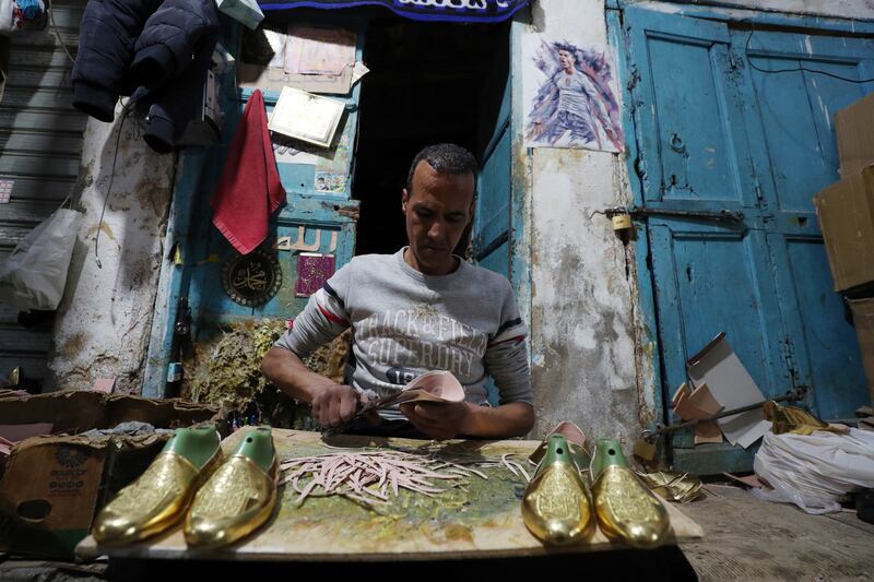 A craftsman manufactures traditional Tunisian shoes in a workshop in the Old Town of Tunis, Tunisia, 22 February 2023.  Traditional leather shoes are made for sale to tourists visiting Tunisia, and they are also exported to Algeria and Libya.  The workshop manufactures 120 shoes a day.   EPA / MOHAMED MESSARA