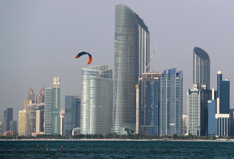 Abu Dhabi, United Arab Emirates - Reporter: N/A: Standalone. A kite surfer performs in the bay in front of the Abu Dhabi skyline at sunset. Monday, April 27th, 2020. Abu Dhabi. Chris Whiteoak / The National