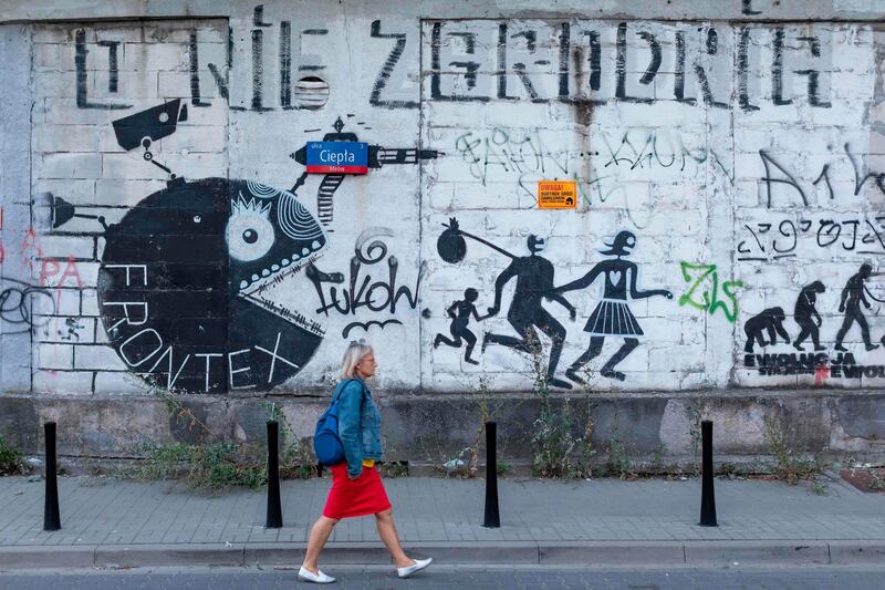 A woman passes by a Frontex- critical mural near the headquarter of the European Union border force Frontex in Warsaw, Poland, on August 5, 2019.  The European Union border force Frontex has allegedly been turning a blind eye to ill treatment of refugees by guards at EU external borders, according to media reports. / AFP / Wojtek RADWANSKI
