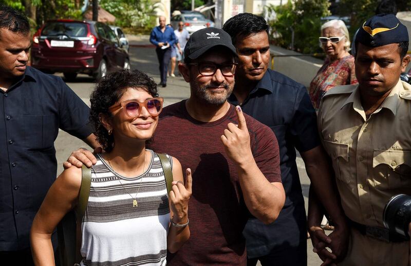 Indian Bollywood actor Aamir Khan (R) along with his wife and film director Kiran Rao (L) pose for photographs after casting their vote at a polling station in Mumbai on April 29, 2019. Voting began for the fourth phase of India's general parliamentary elections as Indians exercise their franchise in the country's marathon election which started on April 11 and runs through to May 19 with the results to be declared on May 23. / AFP / Sujit Jaiswal
