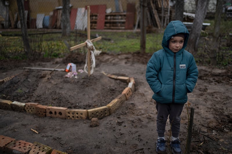In the courtyard of their house, Vlad Tanyuk, 6, stands near the grave of his mother Ira Tanyuk, who died because of starvation and stress due to the war, on the outskirts of Kyiv. AP
