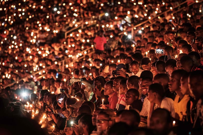 TOPSHOT - People hold candles as they attend a night vigil and prayer at the Amahoro Stadium as part of the 25th Commemoration of the 1994 Genocide, in Kigali, Rwanda, on April 7, 2019. Rwanda on April 7, 2019 began 100 days of mourning for more than 800,000 people slaughtered in a genocide that shocked the world, a quarter of a century on from the day it began. / AFP / Yasuyoshi CHIBA
