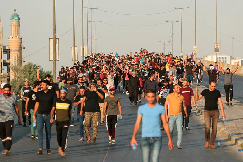 Anti-government protesters walk towards the site of their demonstration in Baghdad.  AP Photo