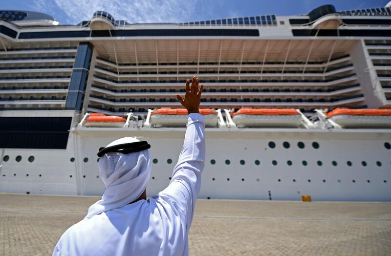An Emirati man waves at the crew members of the AIDA prima, the flagship of AIDA Cruises docked at Port Rashid in the Emirati city of Dubai on April 22, 2020. Dubai has welcomed thirteen foreign cruise ships that were at sea while most countries had closed maritime borders due to the coronavirus pandemic, an Emirati official said.  / AFP / KARIM SAHIB
