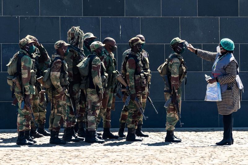 A health worker checks the temperature of soldiers upon their arrival for the burial ceremony of Zimbabwe's agriculture minister Perrance Shiri at the National Heroes Acre in Harare. AFP