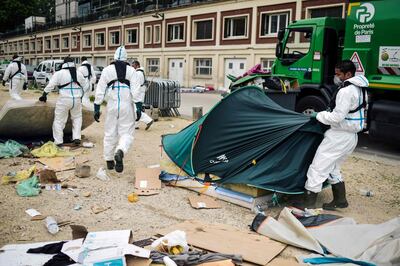 TOPSHOT - Workers clean up a migrants' makeshift camp along the Canal de Saint-Martin at Quai de Valmy in Paris, following its evacuation on June 4, 2018. More than 500 migrants and refugees were evacuated on early June 4, 2018 from a makeshift camp that had been set up for several weeks along the Canal. / AFP / Lucas Barioulet
