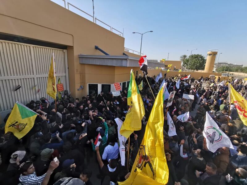 Protesters and militia fighters gather outside the main gate of the US Embassy in Baghdad. Reuters
