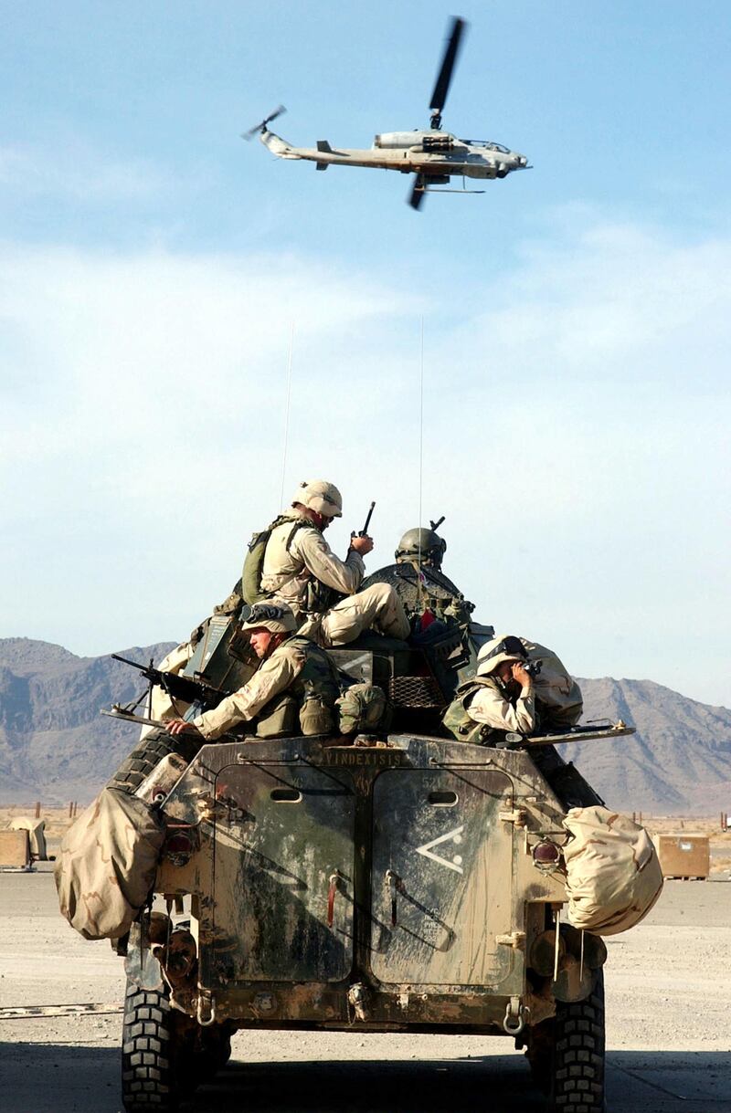 399162 03: Marines on a Light Armored Vehicle prepare for patrol as an AH1W "Super Cobra" helicopter flies by December 28, 2001 at the U.S. Marine Corps Base in Kandahar, Afghanistan. U.S. Marines are in Afghanistan in support of Operation Enduring Freedom. (Photo by Johnny Bivera/U.S. Navy/Getty Images)