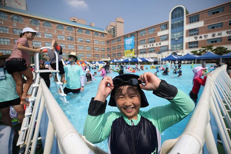 Students play in a swimming pool set up in a school playground in northern Seoul. EPA