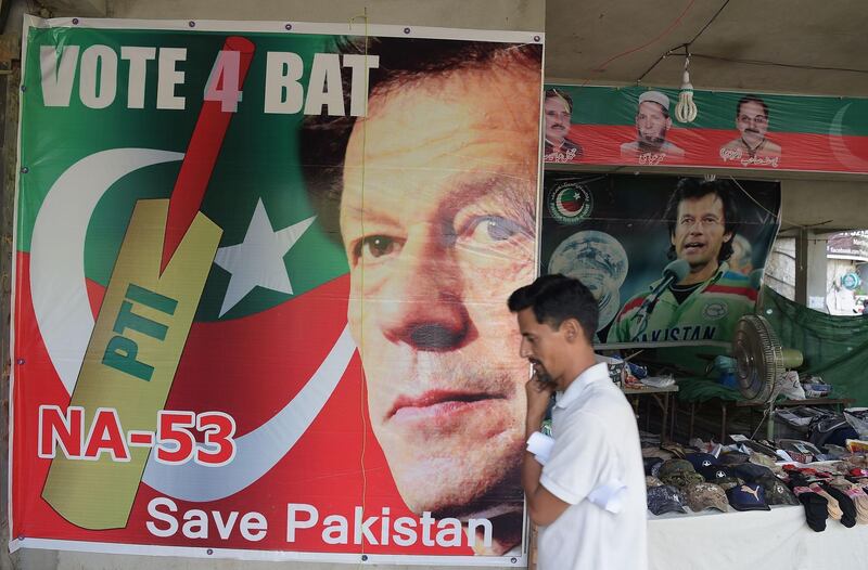 A man walks past a poster of Pakistan's cricketer-turned politician Imran Khan, and head of the Pakistan Tehreek-e-Insaf (Movement for Justice) party, at a market in Islamabad on July 27, 2018. Cricket hero Imran Khan has swept to an emphatic victory in a disputed Pakistan election, but without a majority he will need to enter a coalition to take power in the nuclear-armed country. / AFP / AAMIR QURESHI
