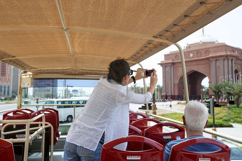 A tourist takes a picture of Emirates Palace on The Big Bus Tour. Mona Al Marzooqi / The National