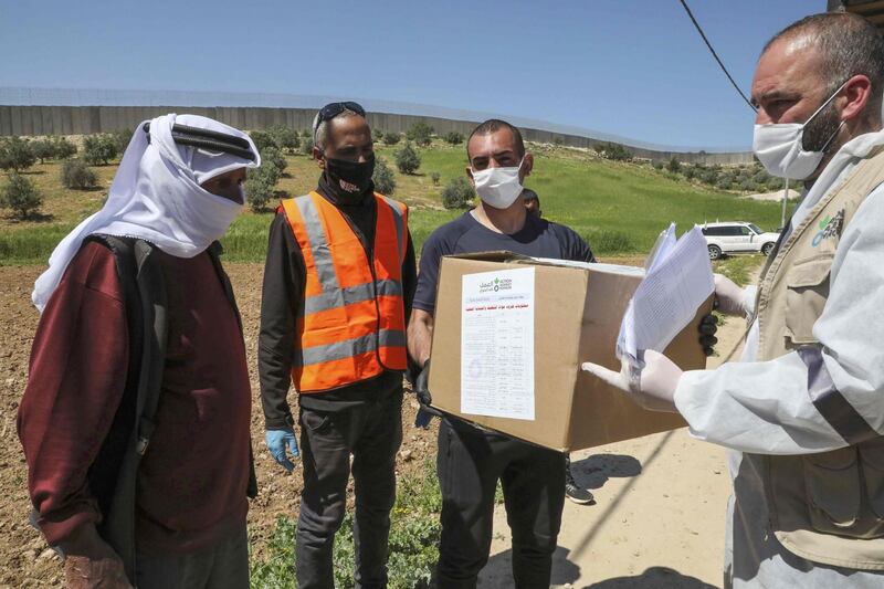 Members of the French Action Against Hunger NGO distribute hygiene and sanitation products to Palestinian residents of al-Ramadin village, southwest of the West Bank town of Hebron.   AFP