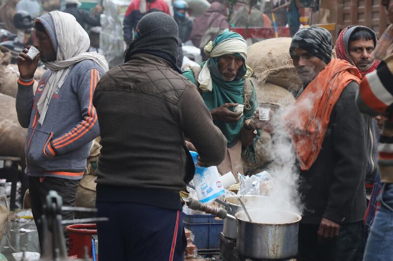 epa08095597 People line up at a tea stall on a cold morning in New Delhi, India, 31 December 2019. Northern India remains in the grip of cold as minimum temperature in the national capital New Delhi dropped below the three degrees Celsius mark.  EPA/RAJAT GUPTA